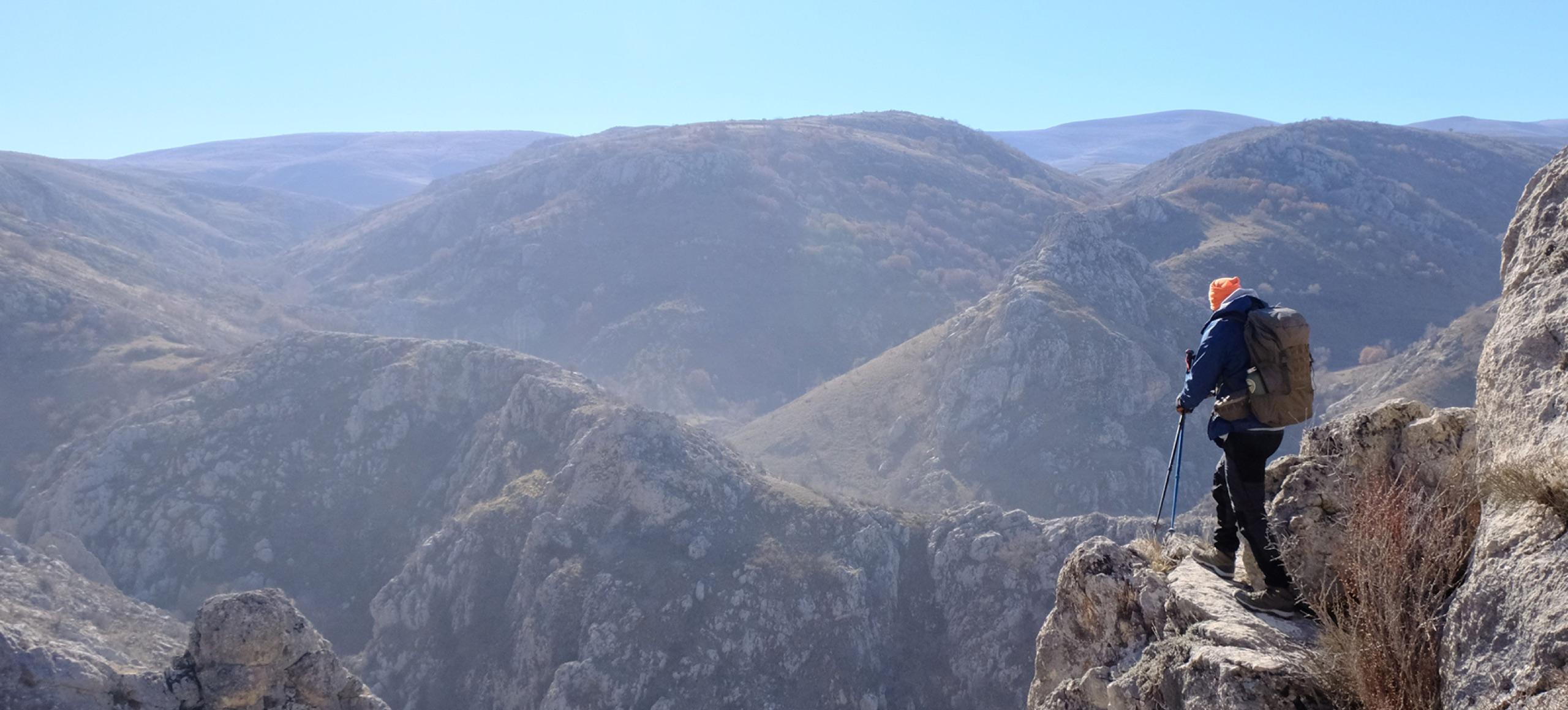 Excursionista con mochila en un mirador, frente a un valle de montaña